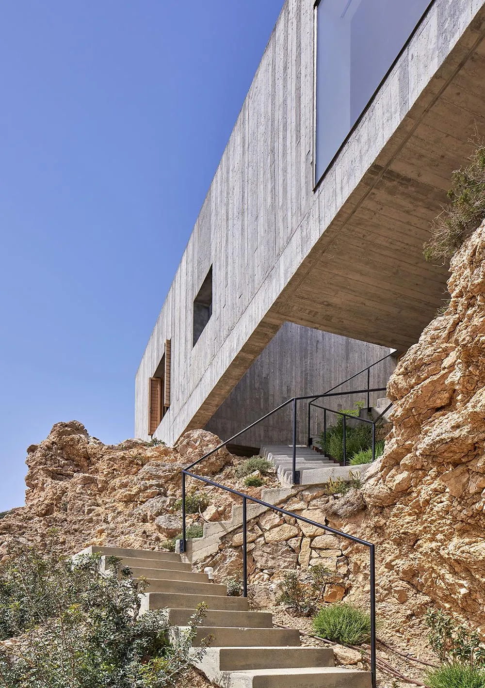 Modern residential house with concrete exterior on a rocky cliffside