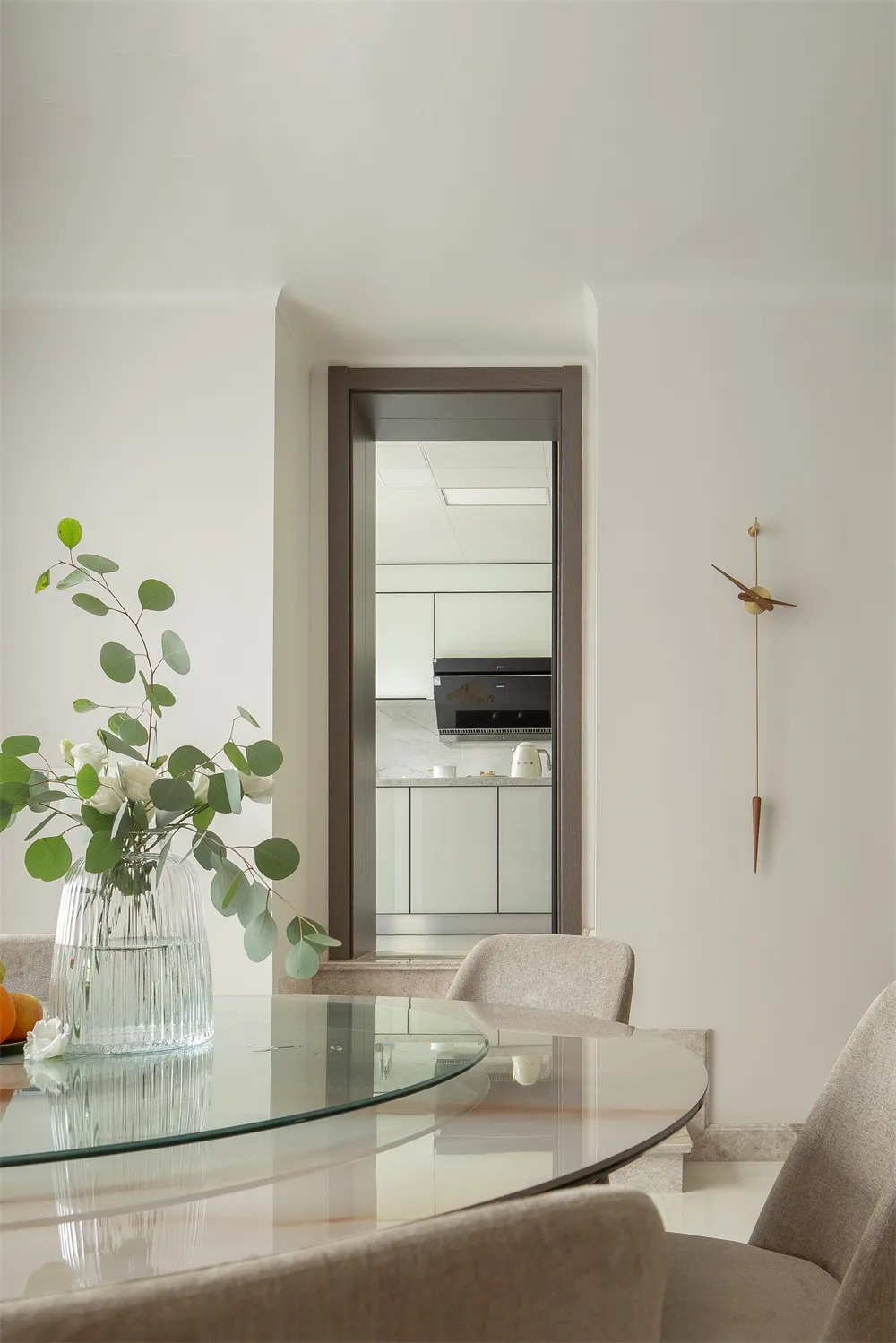 Modern minimalist kitchen with glass table, marble countertops, and wooden accents.