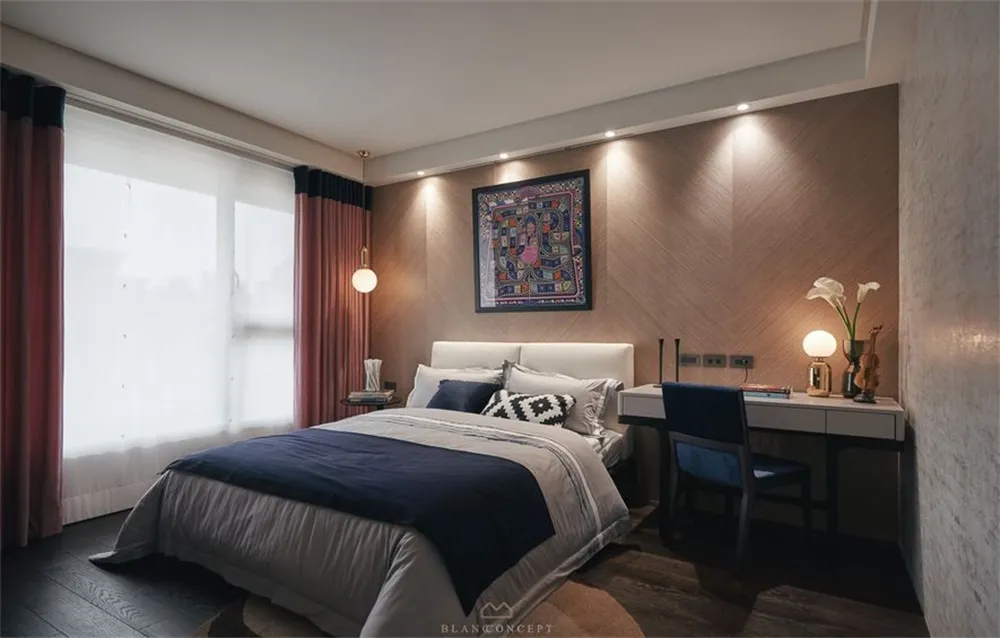 A modern bedroom featuring a bed with textured wooden paneling, blue bedding, and a wooden desk with a chair and table lamp.