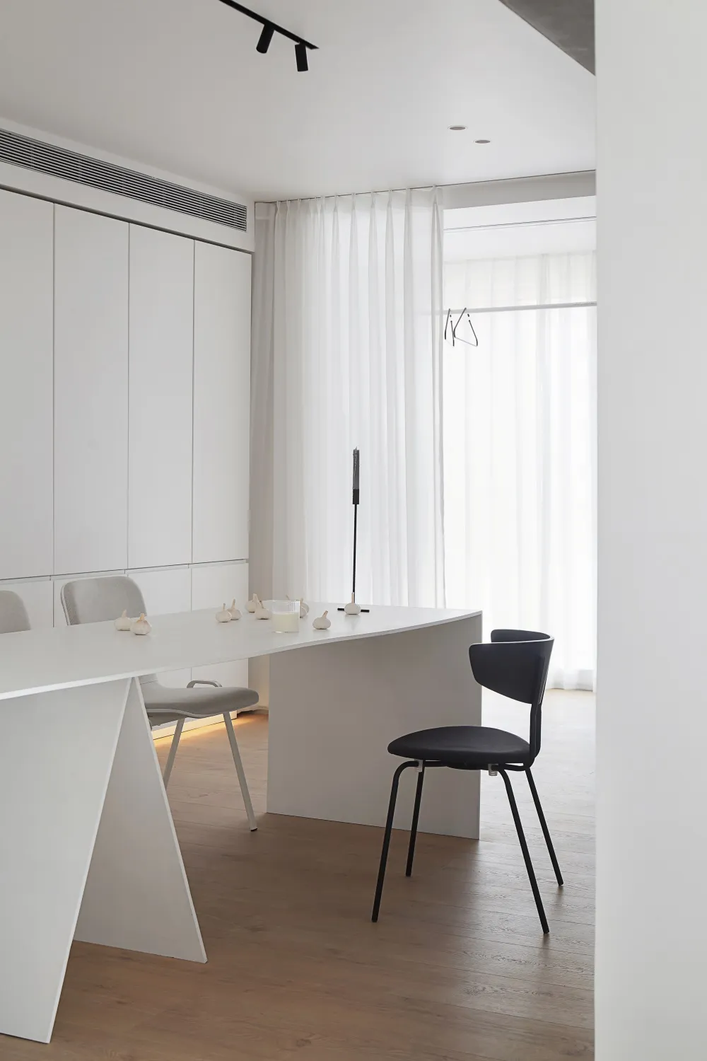 Modern, minimalist kitchen interior with white cabinets, counter, and seating area. Features sleek, clean design.