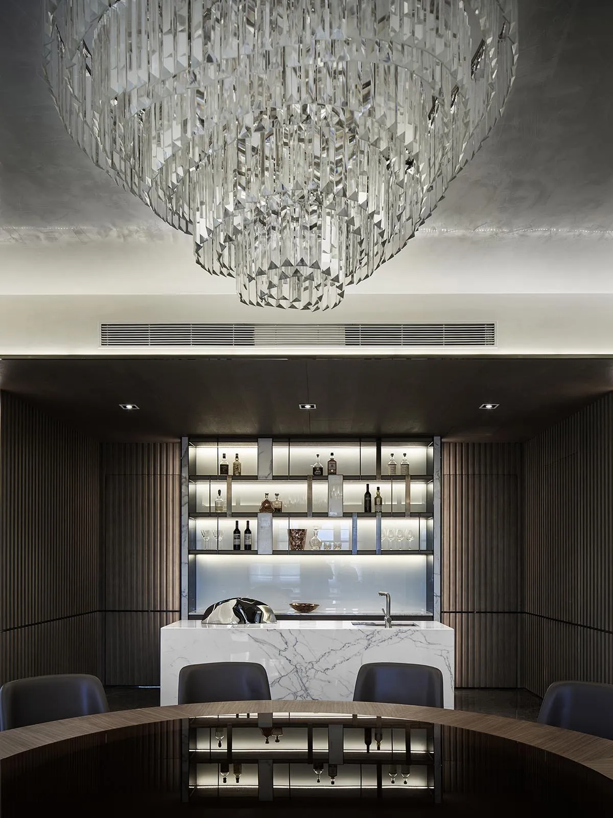 Modern dining room with a bar area showcasing marble countertops and a luxurious chandelier.