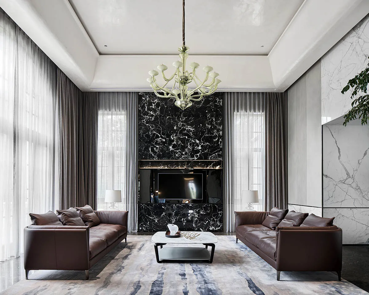 Modern living room featuring marble accent wall, concrete floor, and leather sofas.