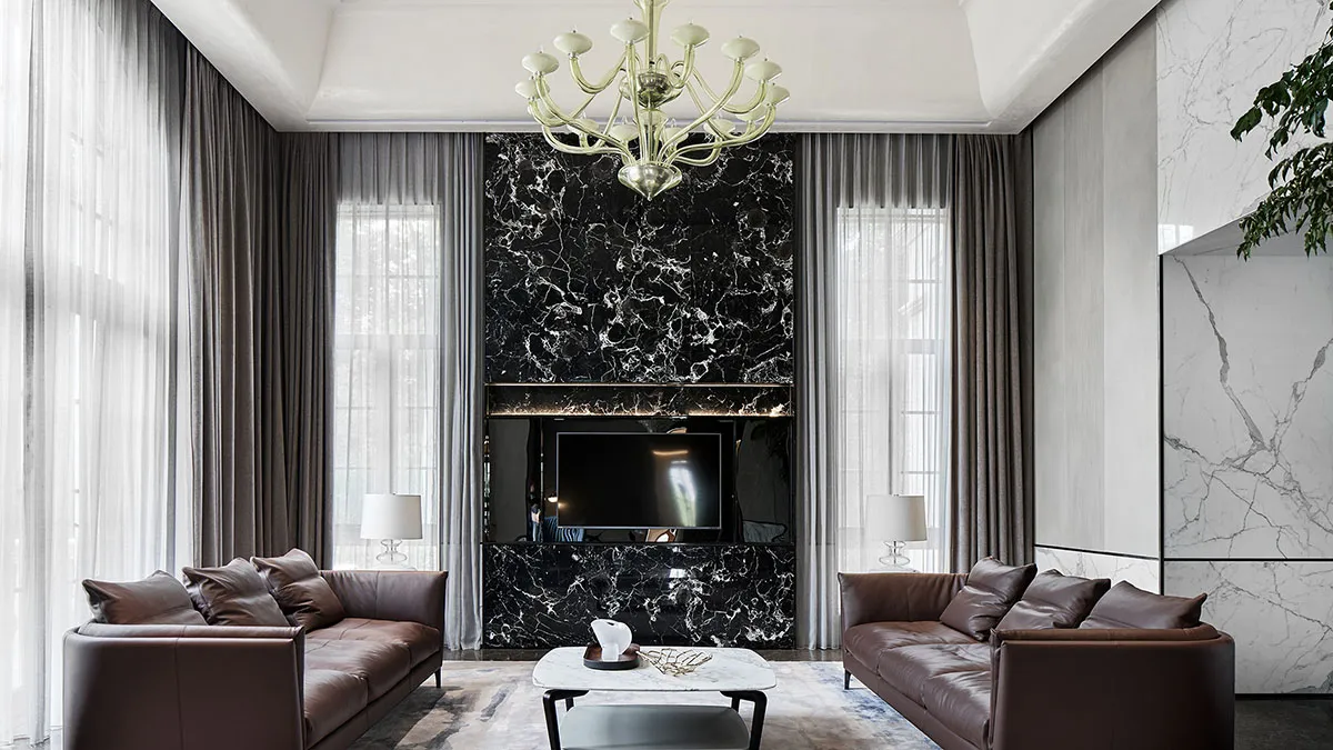 Modern living room featuring a black marble accent wall, brown leather sofas, and a marble coffee table.