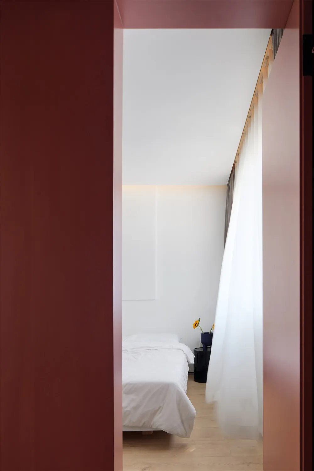 Modern minimalist bedroom with vertical space utilization, white bedding, and minimalistic design.