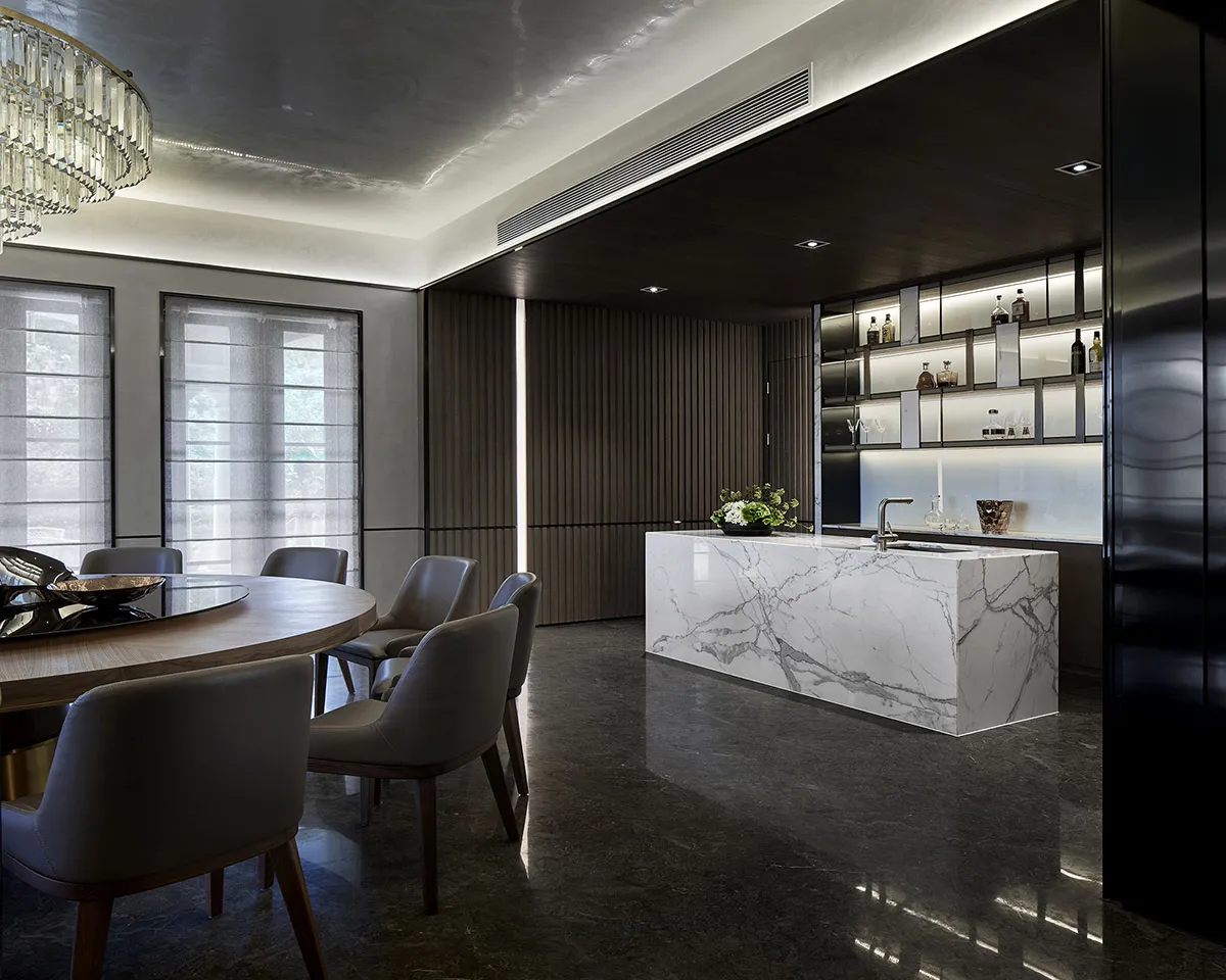 Modern residential kitchen featuring a marble countertop and a round dining table with gray chairs.