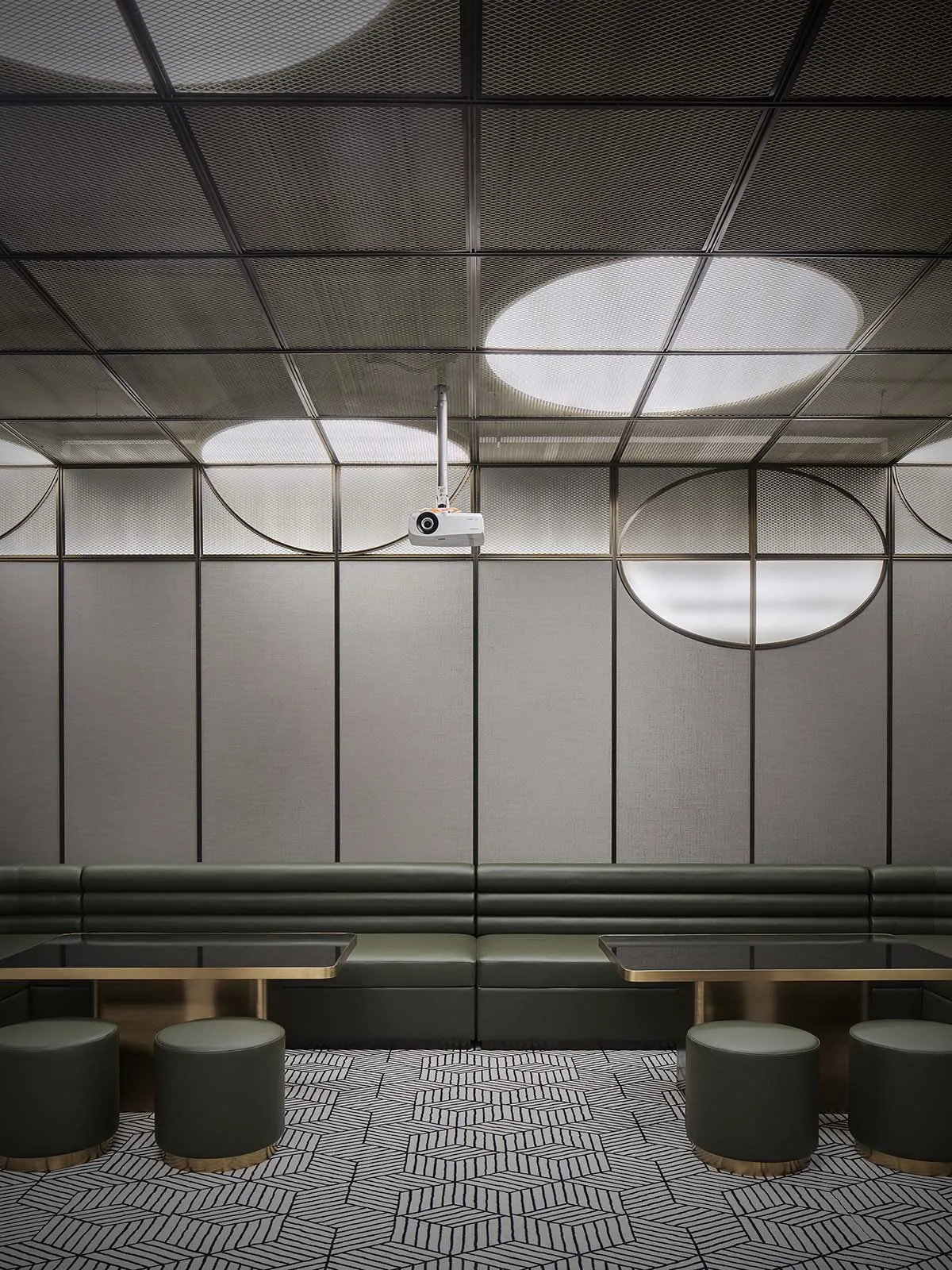 Modern industrial restaurant dining room with metallic textured panels and green leather seating.