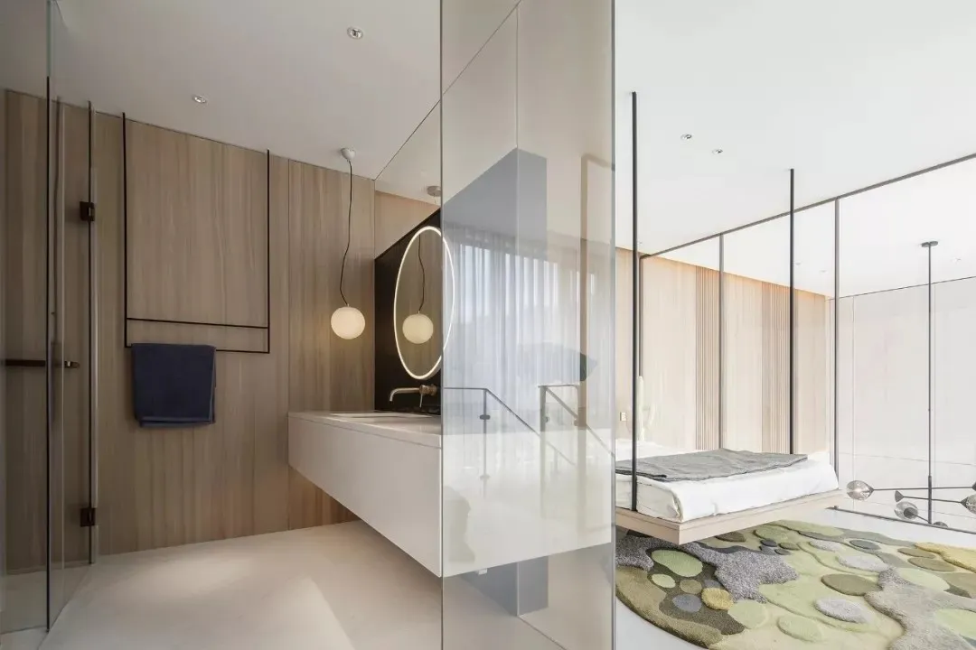 Modern minimalist bedroom featuring a wooden-paneled wall, white furniture, and a circular mirror with wooden frame.