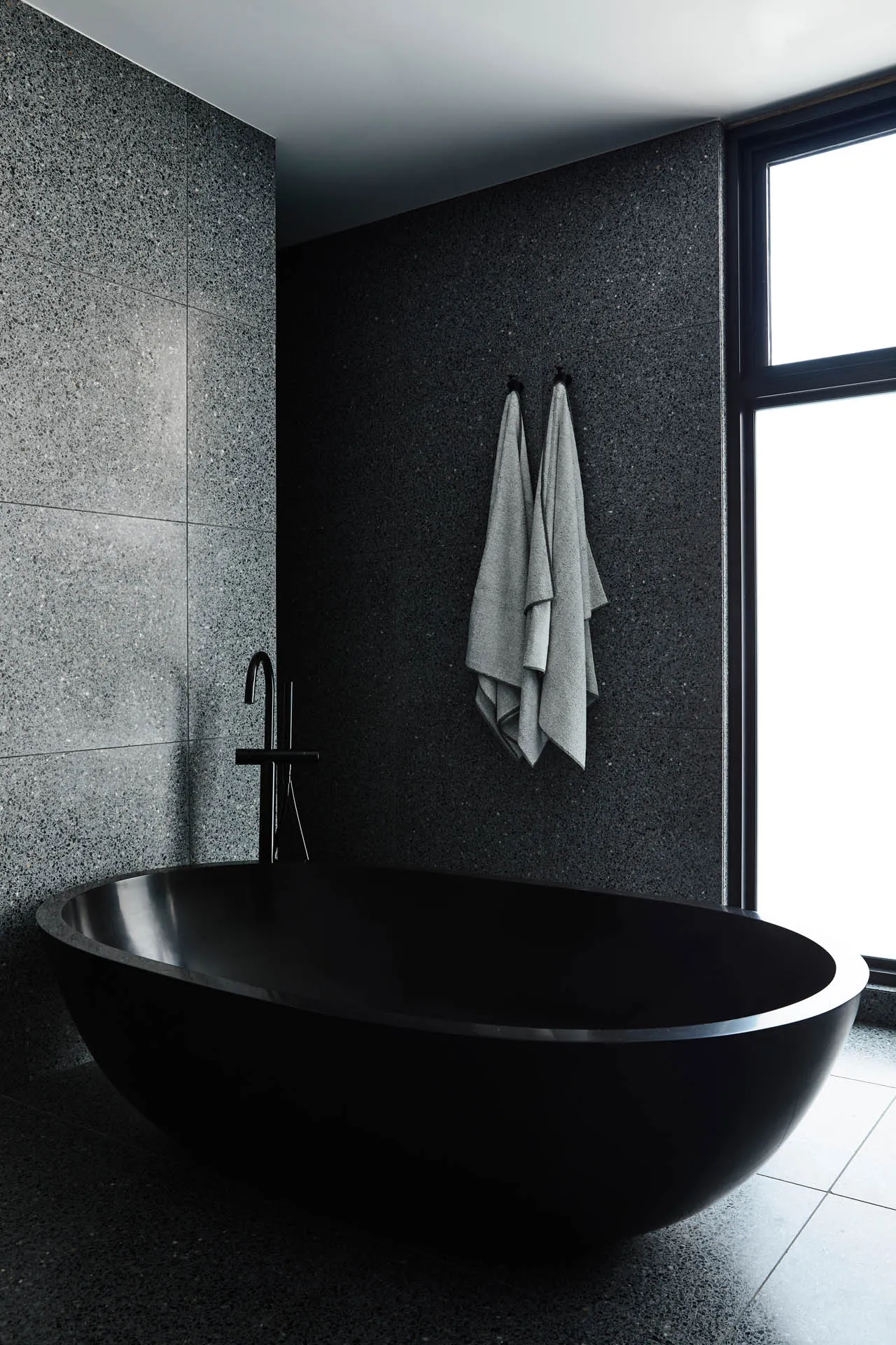 Modern minimalist bathroom featuring a sleek black bathtub made of marble.