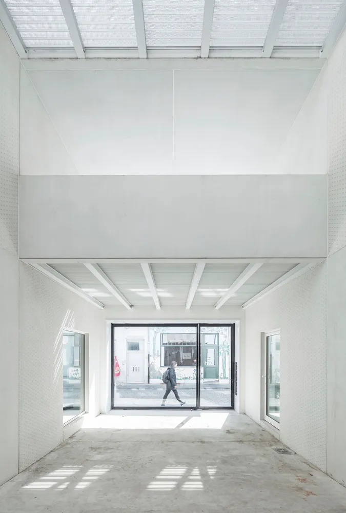 A minimalist retail space with concrete walls and floor, large glass doors and windows.