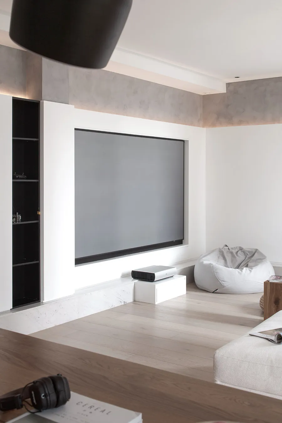 A minimalist home theater with a large projection screen, projector, and comfortable seating.