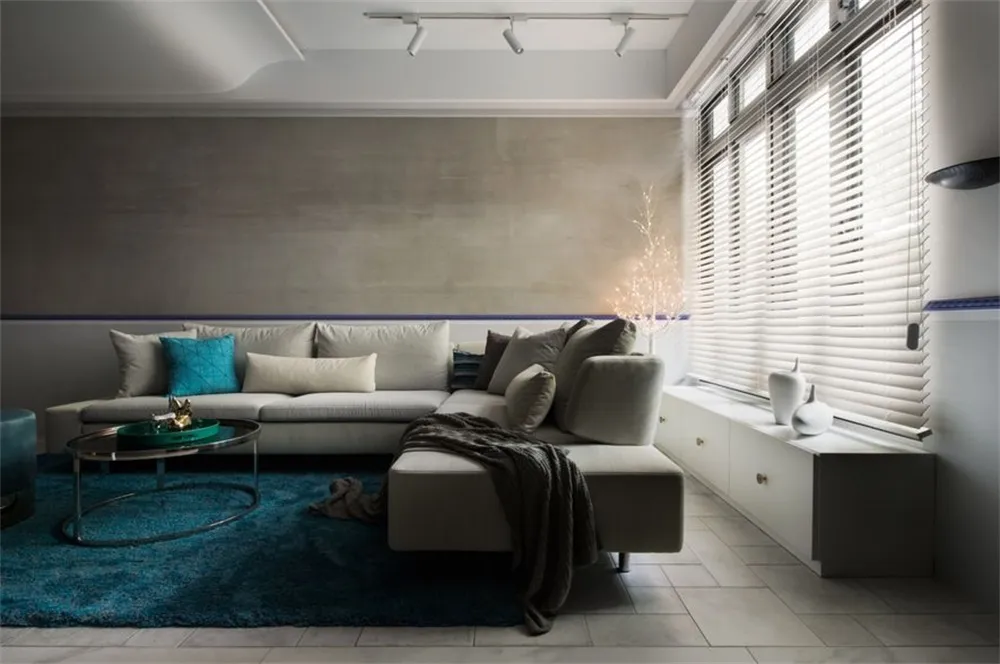 A modern industrial living room with concrete walls and a gray sectional sofa.