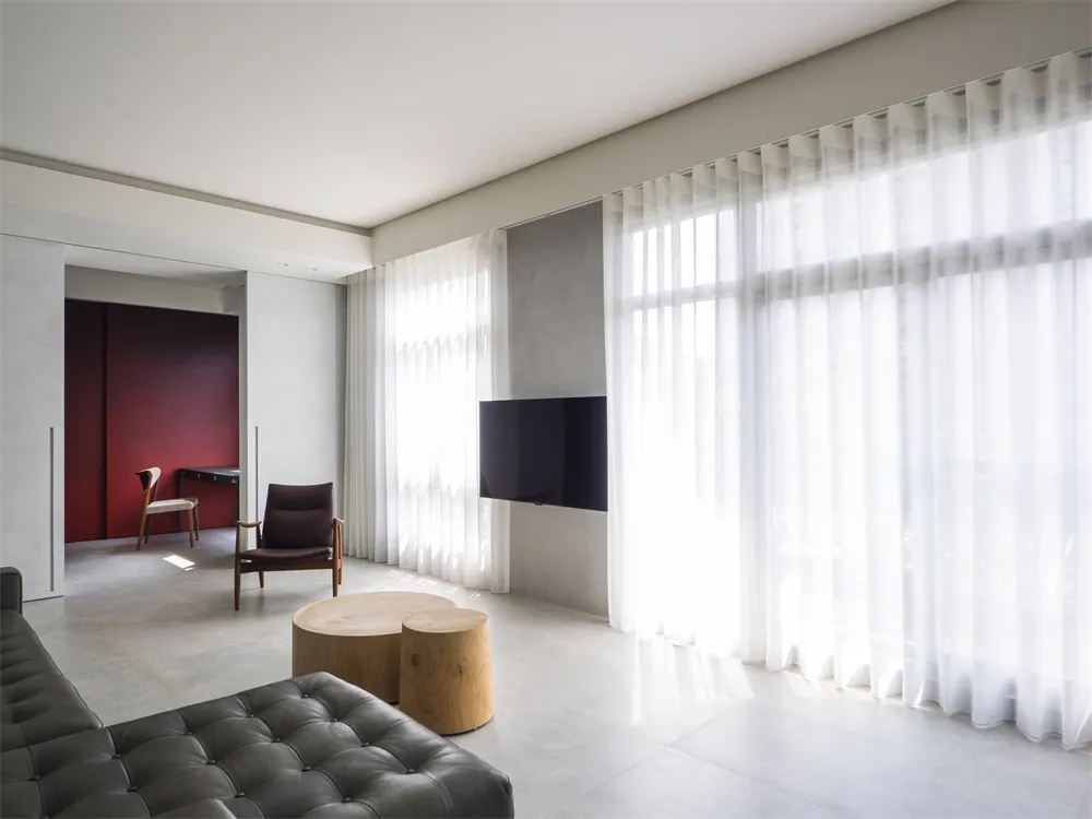 Modern living room with concrete flooring, glass walls, and minimalist furniture.