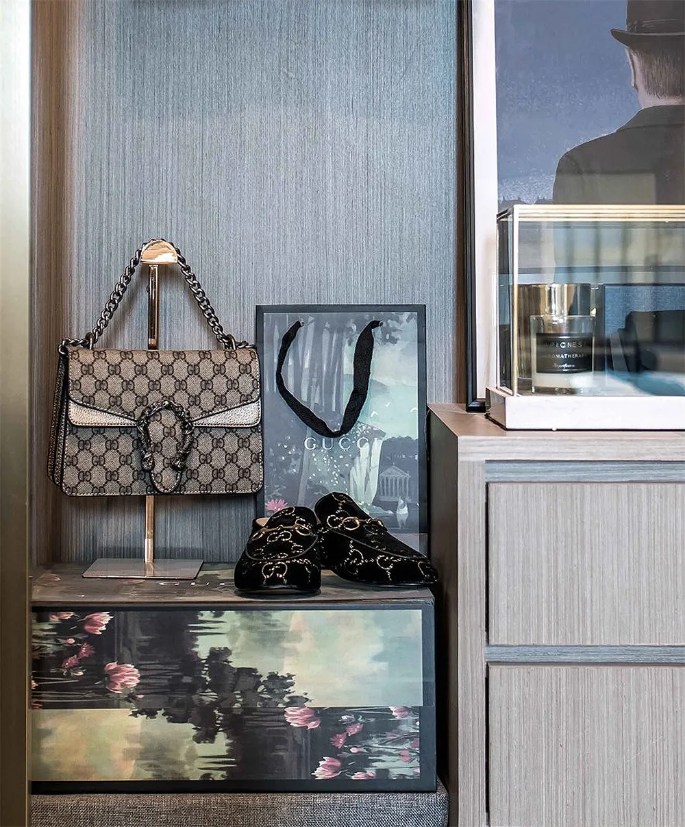 A luxury retail display featuring a Gucci purse, loafers, and a framed picture on a wooden dresser.
