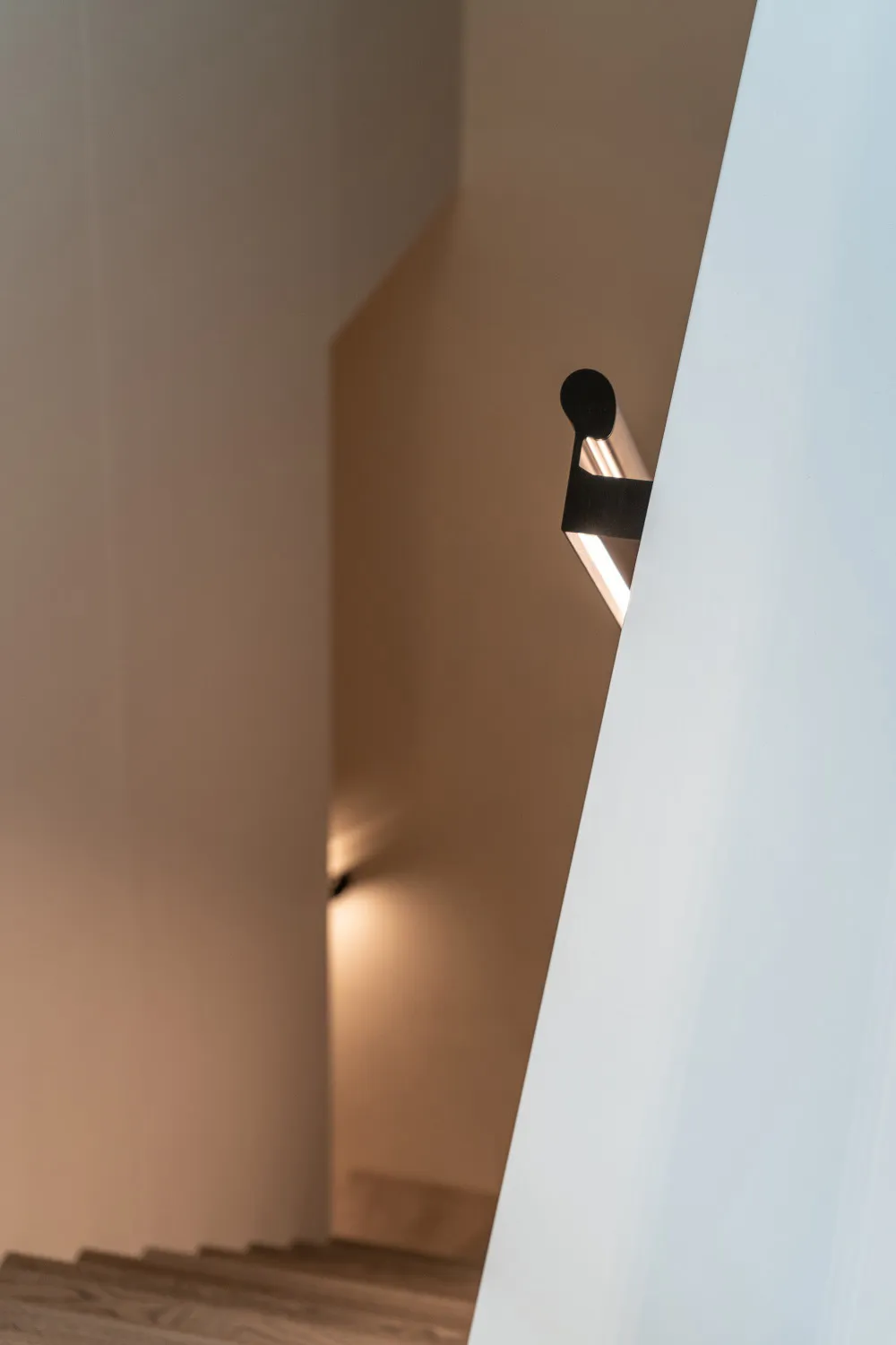 Modern minimalist staircase with wooden treads and a modern light fixture.