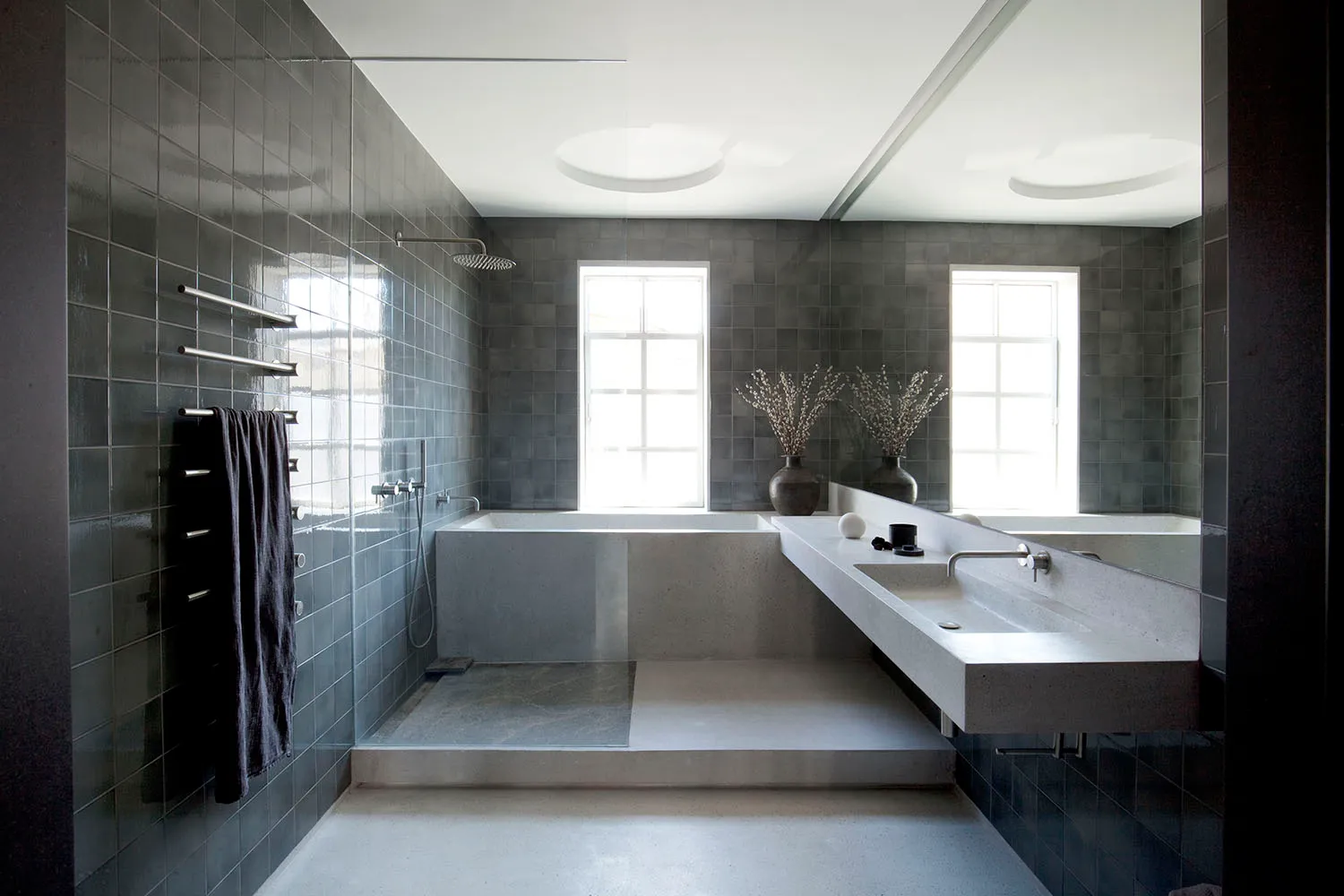 A minimalist bathroom featuring grey tiles, concrete elements, and a contemporary design.