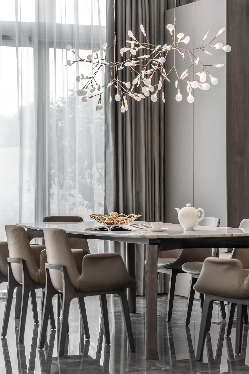 Modern dining room featuring a marble table and walnut chairs with a unique chandelier and an open window with sheer curtains