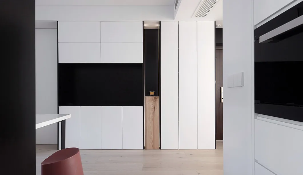 Modern interior design featuring minimalist white cabinets with black accents in a contemporary apartment setting.
