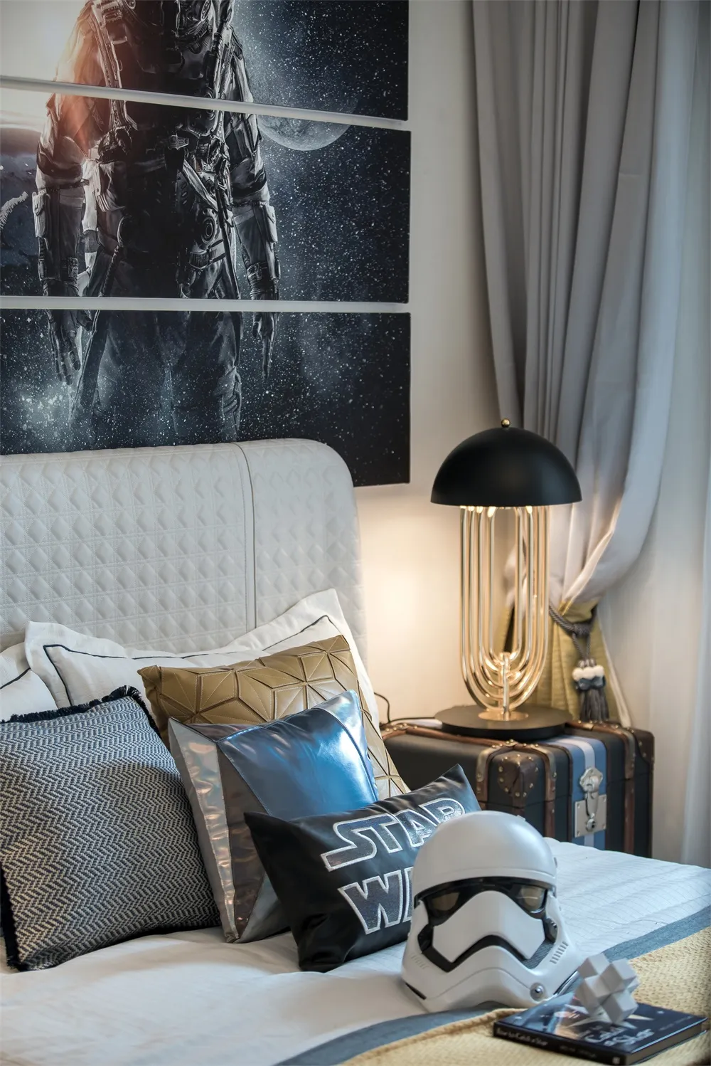 Bedroom featuring a white upholstered headboard with various pillows and a stormtrooper helmet on the bed.