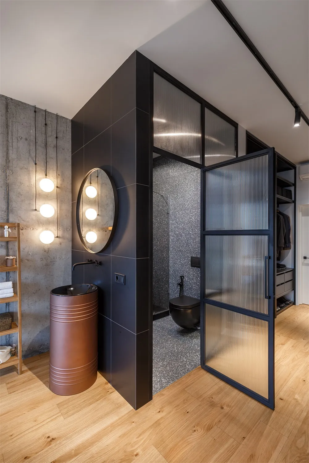 Modern minimalist bathroom with concrete walls, black tiles, and glass shower door.