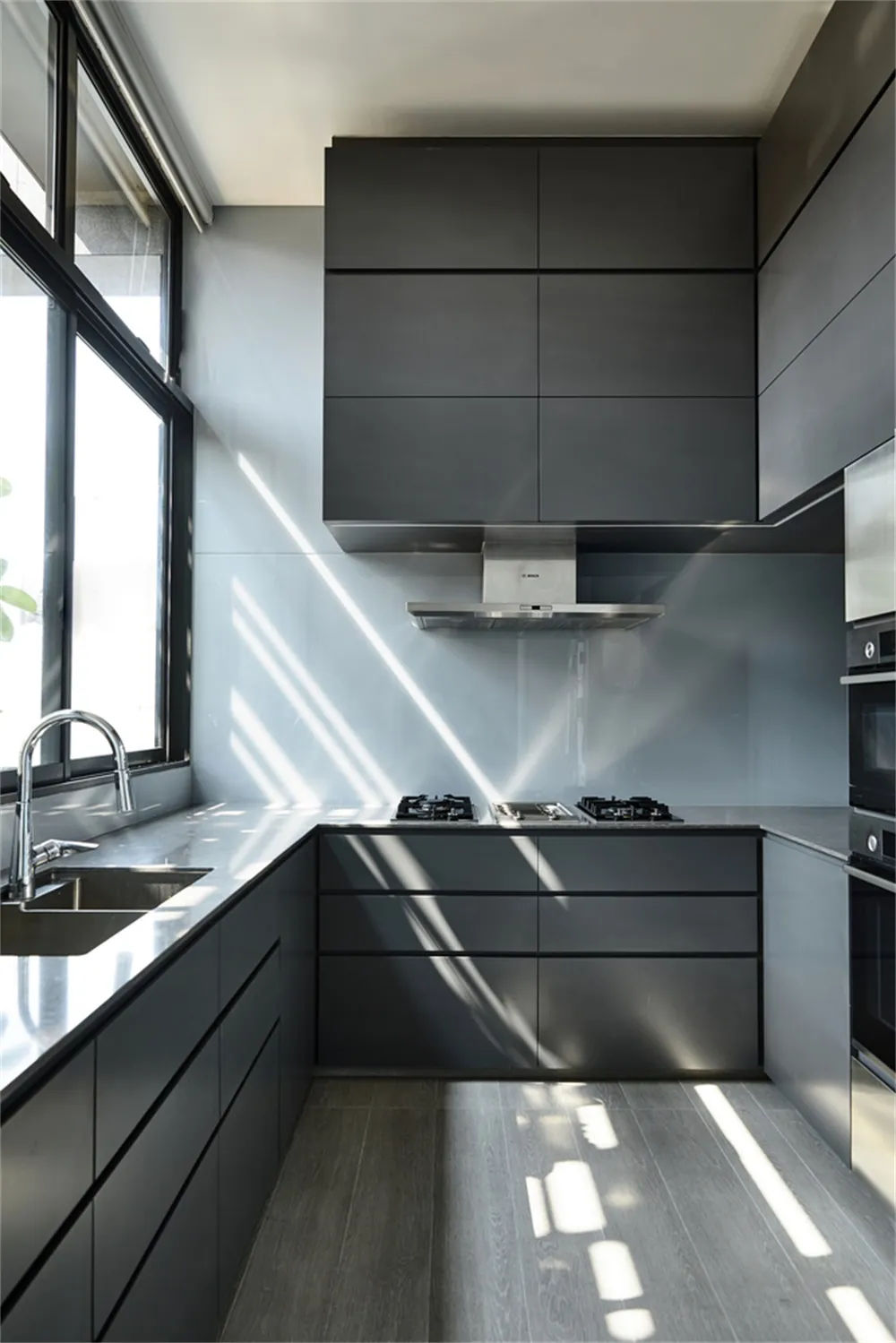 Modern kitchen featuring sleek black cabinets and glass countertops.