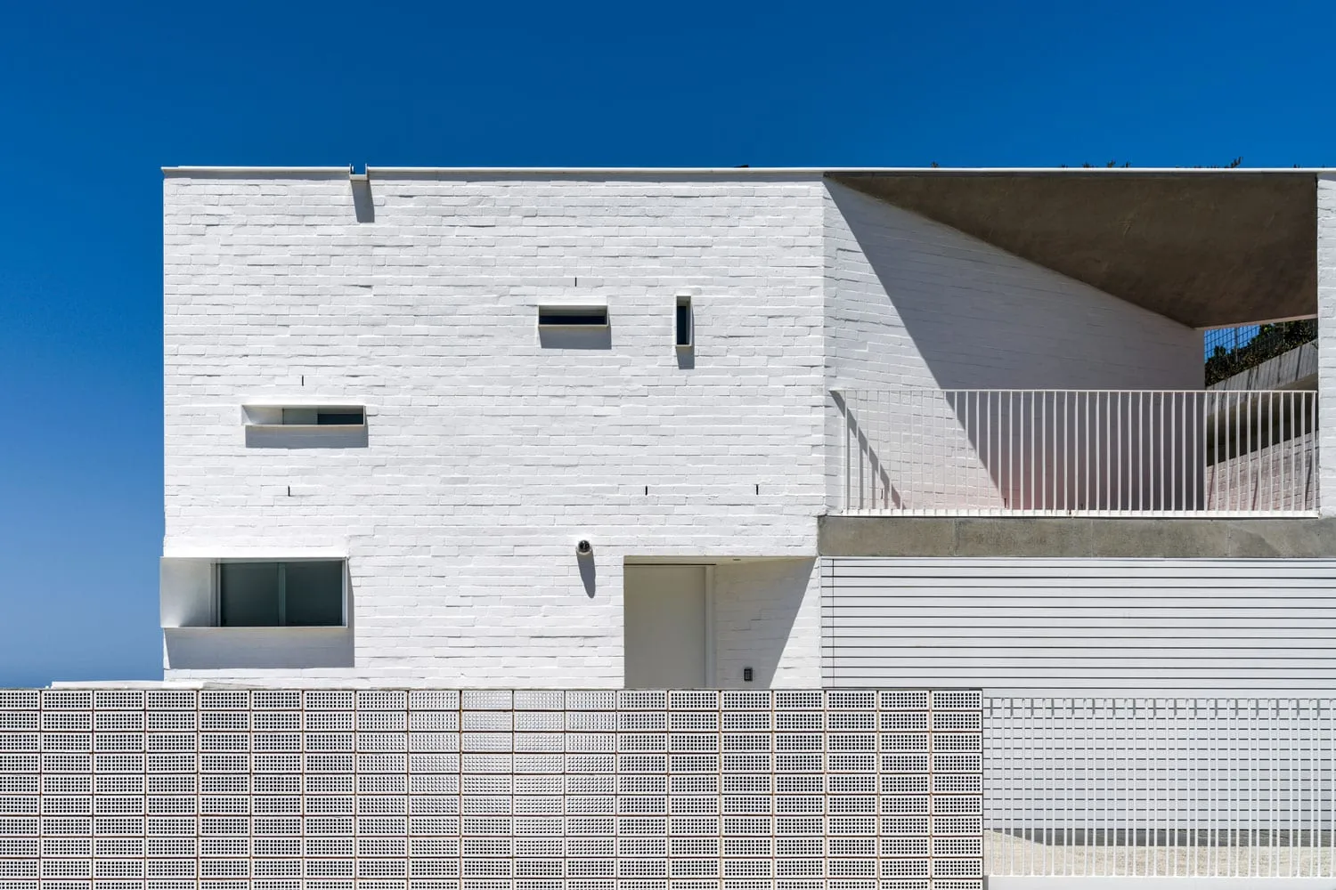 A modern building facade with concrete walls and a white brick wall.