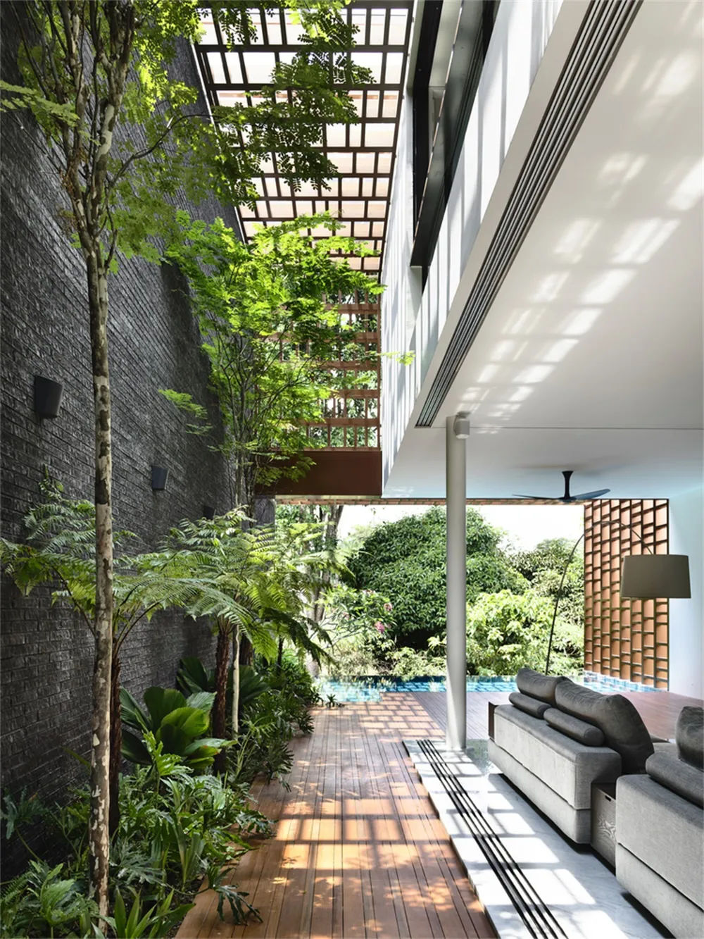 A modern living space with a wooden floor, greenery, and a pool in the middle of the room.