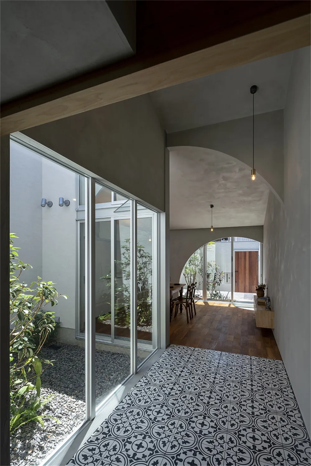 An entryway with concrete walls and a patterned tile floor, showcasing minimalist design elements.
