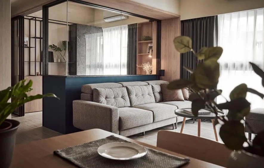 Modern minimalist living room featuring a gray sofa and wooden floor.