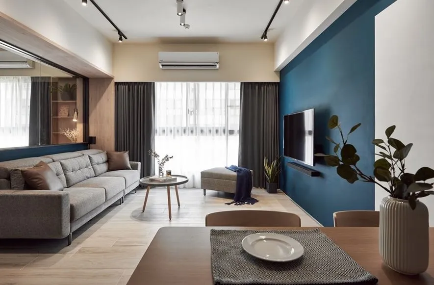 Modern minimalist living room with gray sofa, wooden coffee table, and large windows.