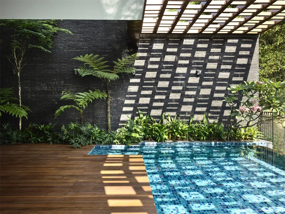 A modern swimming pool with blue tiled interior and brick walls.