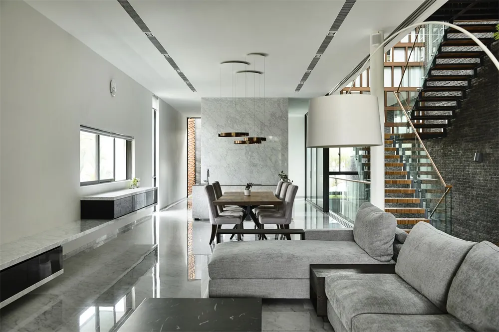 Modern living and dining space featuring marble and concrete finishes, stainless steel accents, and contemporary furniture.