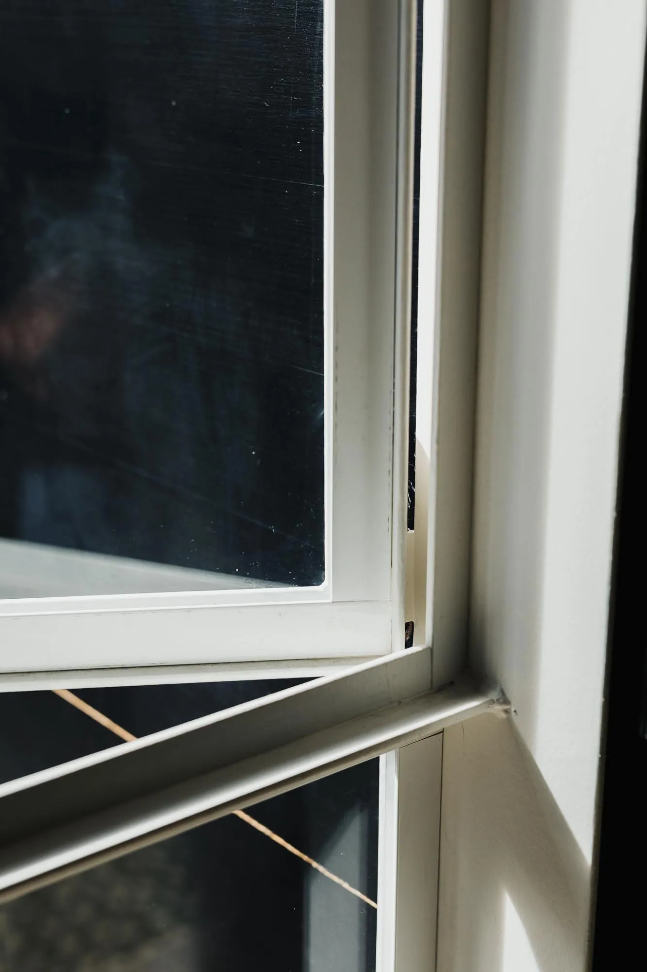 Close-up of a minimalist metal-framed window with sunlight shining through the glass.