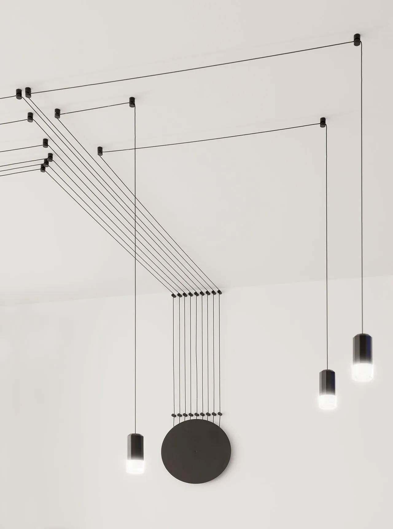 A modern lighting installation featuring a black cable structure and cylindrical light fixtures.