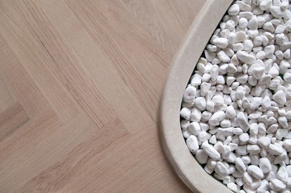 White and grey pebbles arranged in a round container on grey wooden floor