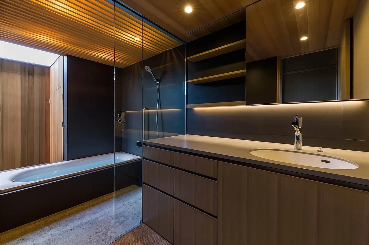 A modern bathroom featuring glass shower enclosure and wooden accents.