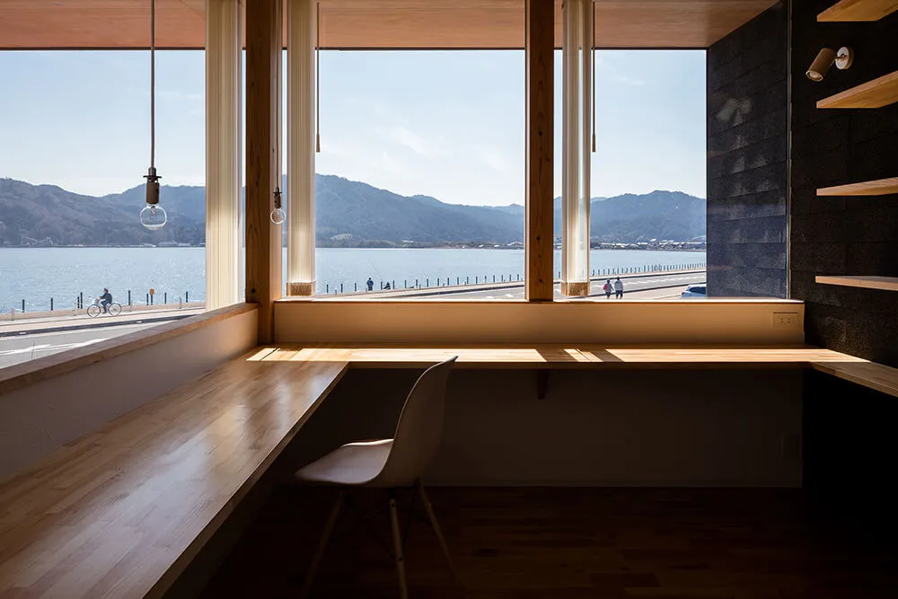 A modern office space featuring a corner window and wooden furniture.