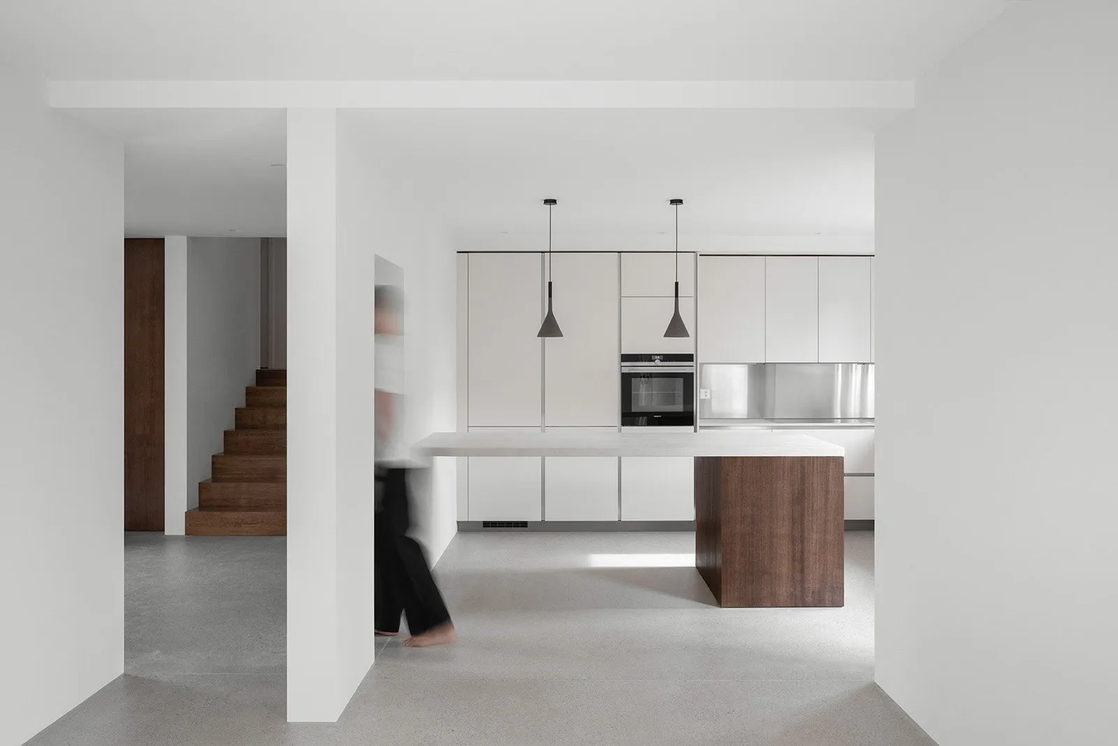 Modern residential kitchen featuring concrete flooring and stainless steel appliances and fixtures.
