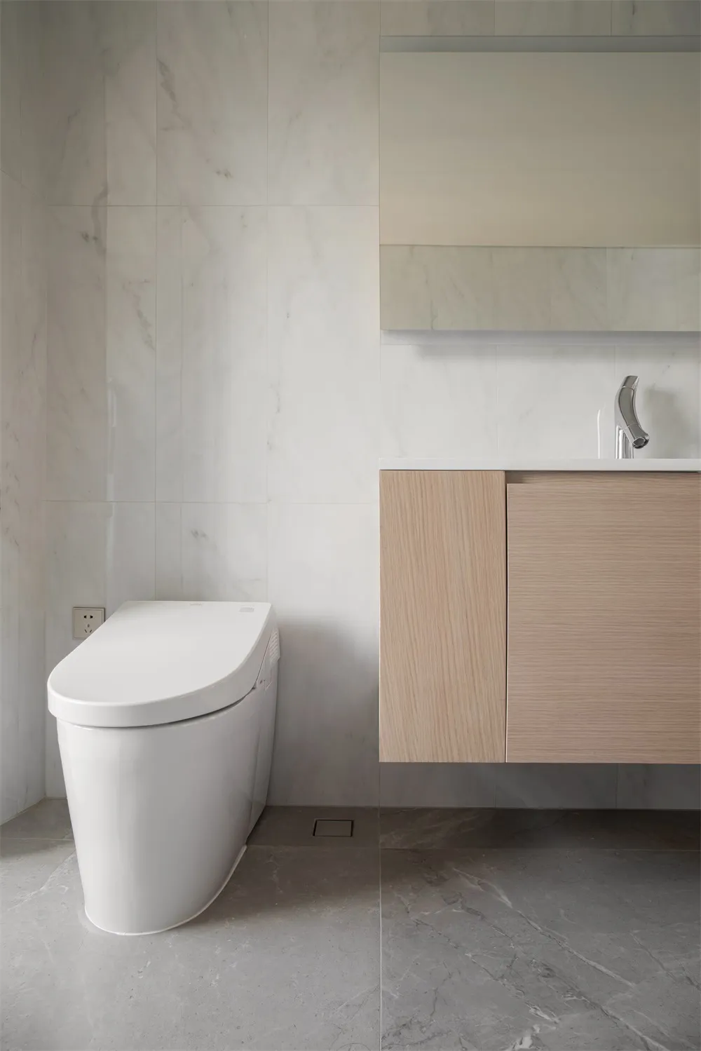 Modern bathroom with minimalist marble design and white toilet.