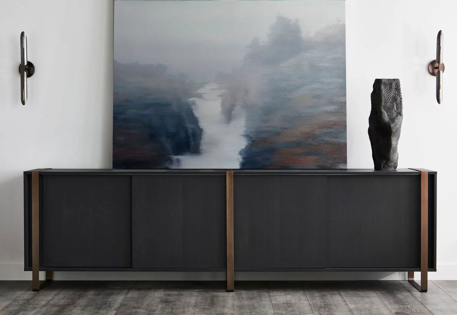 Contemporary black wooden and metal sideboard with minimalist design, featuring abstract artwork and wall sconces.