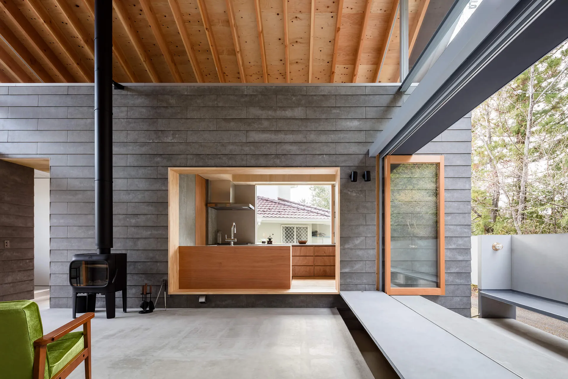 Modern kitchen with concrete and wood materials, featuring an open layout and natural light.