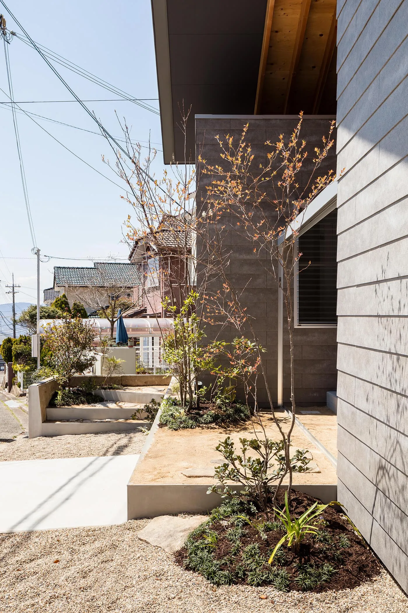 A modern residential garden featuring concrete planters and wooden structures.