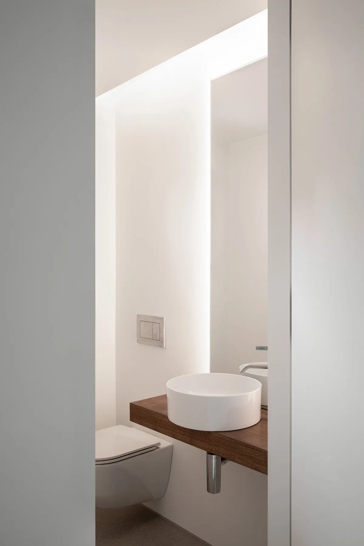 Modern minimalist bathroom with a wooden countertop and porcelain sink.