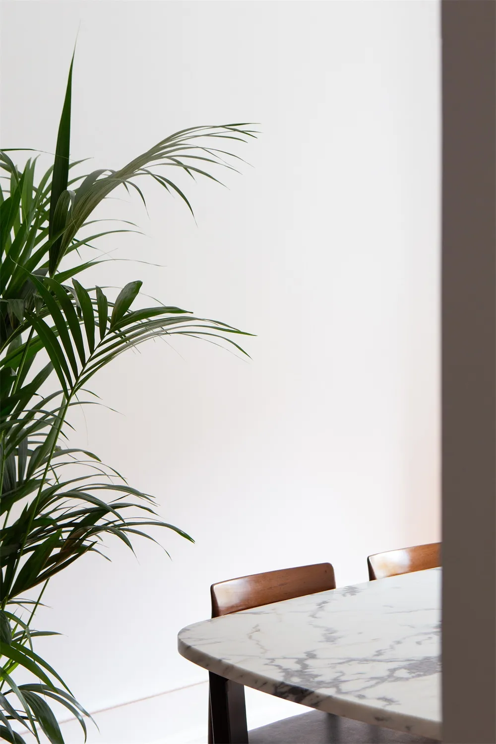 A minimalist dining room featuring a marble table and wooden chairs.