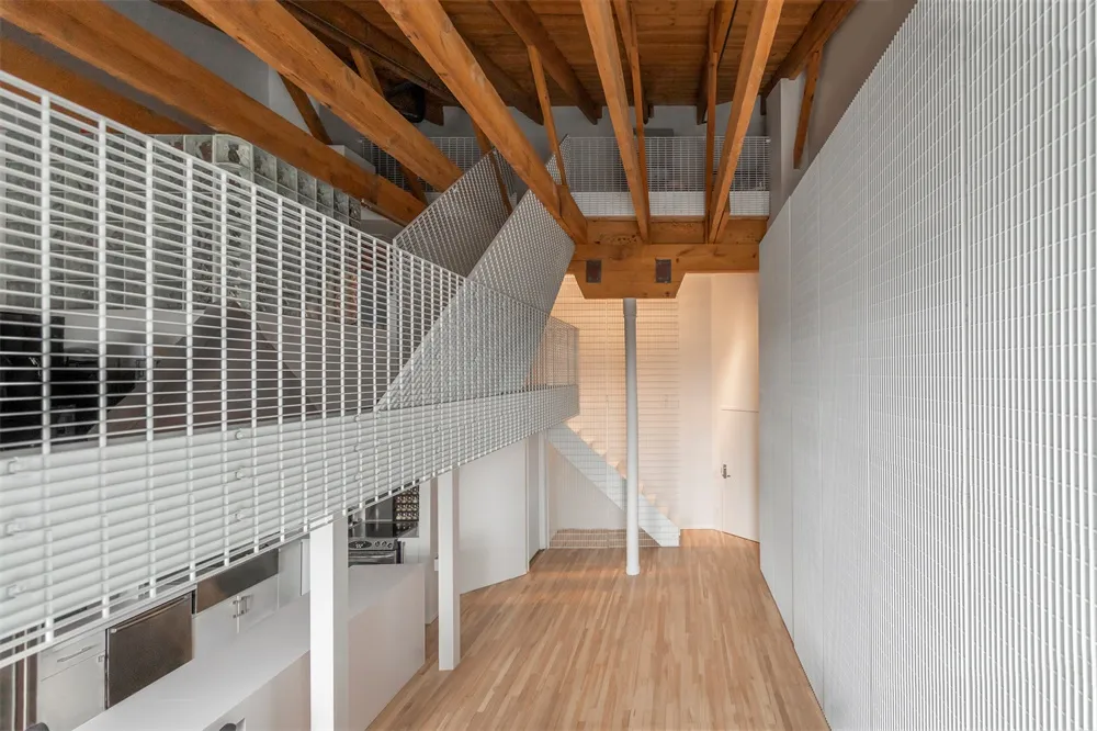 Modern interior with a metallic and wooden staircase illuminated by ambient lighting.