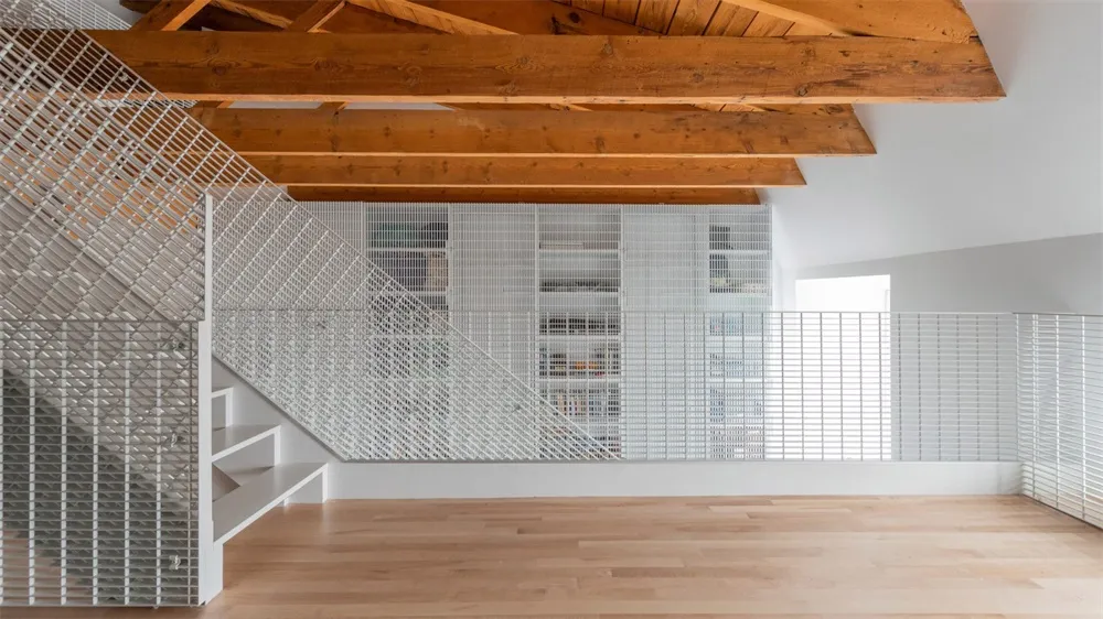 Industrial-style staircase with metal railings and wooden ceiling beams.