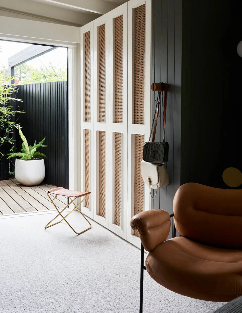 A mid-century modern lounge room featuring a brown leather armchair, white leather ottoman, and a white and brown basket in f