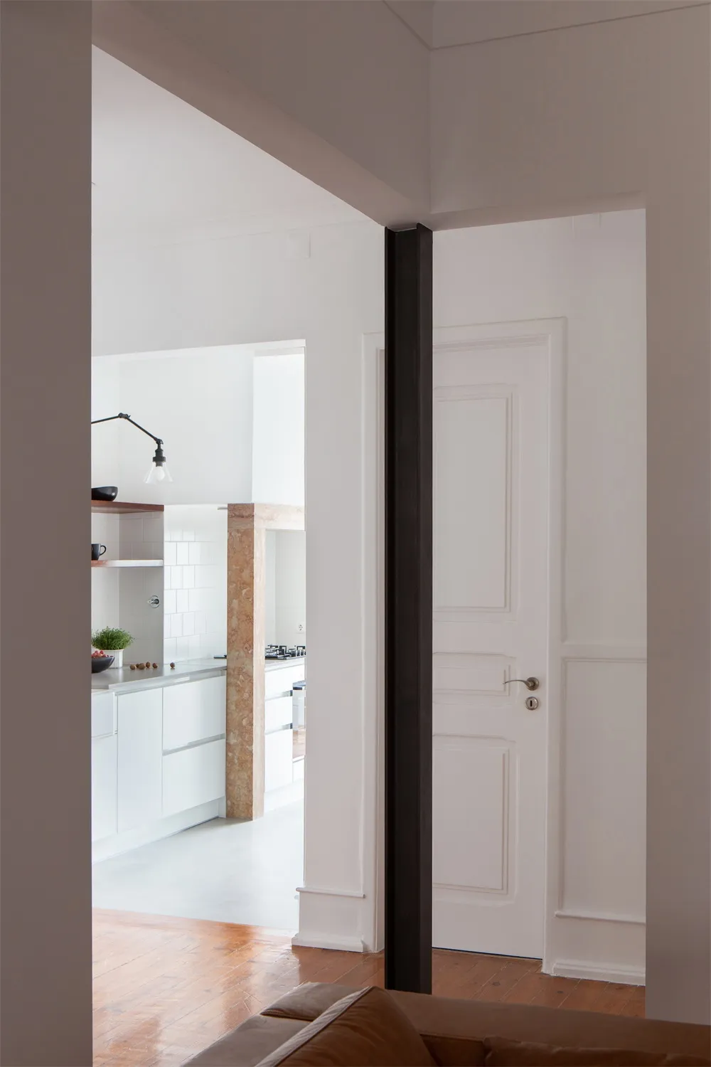 A minimalist kitchen with white flooring, showcasing sleek white cabinetry and modern design elements.