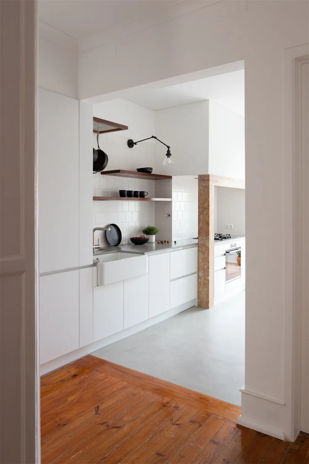 A modern minimalist kitchen with white cabinetry and a concrete floor.