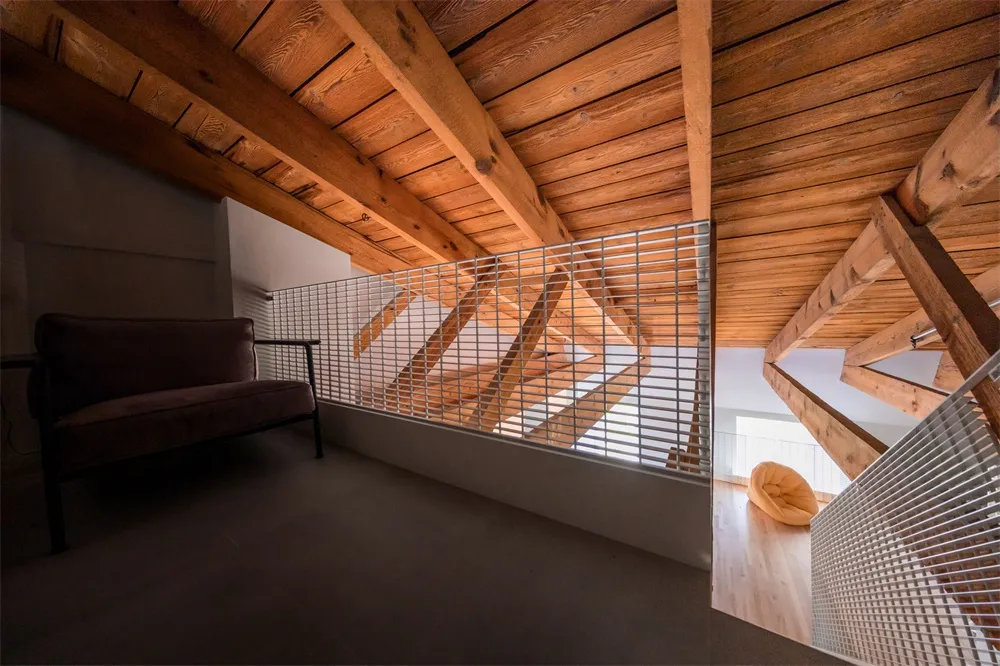 Modern industrial living room with exposed wooden beams, featuring minimalist furnishings and a cozy ambiance.