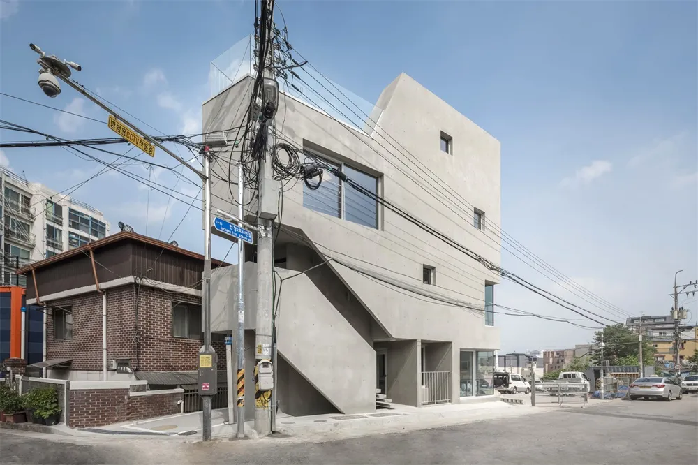 A modern residential building with a concrete exterior and glass windows.